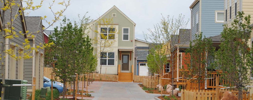 Photograph showing houses lining a very narrow paved lane shared by pedestrians, bicyclists, and automobiles.