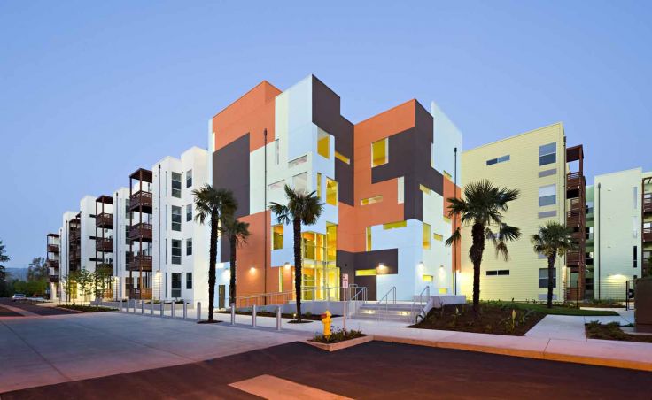 View from across the paseo of one of the four-story buildings with bold geometric forms, some highlighted by different colors (Courtesy of Jeffrey Peters Vantage Point Photography).