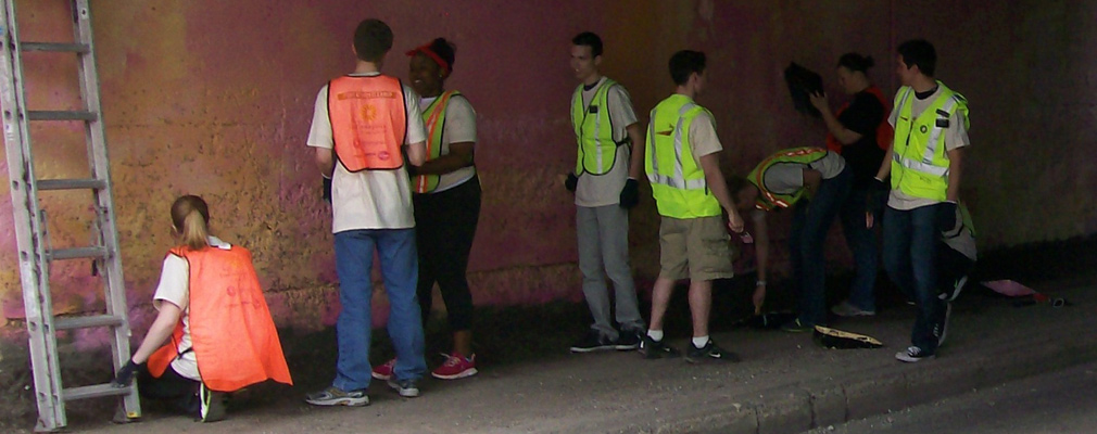 Photograph of students cleaning and painting the wall of an underpass.