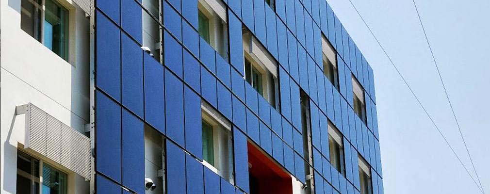 Photograph of vertical solar panels hung on the side of a five story building.