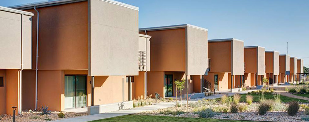 Photograph showing the western façades of the two-story townhouses with sliding glass doors on the first floor and no windows.