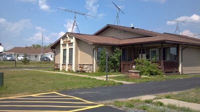 Exterior view of a single-story 2-bedroom apartment in a 4-unit multifamily building, featuring a recessed front porch with railings.