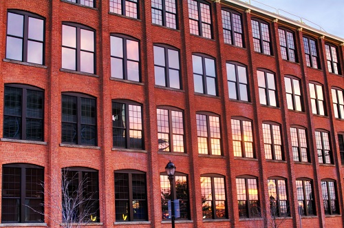 Photograph of the brick façade of a four-story industrial building with arched windows.
