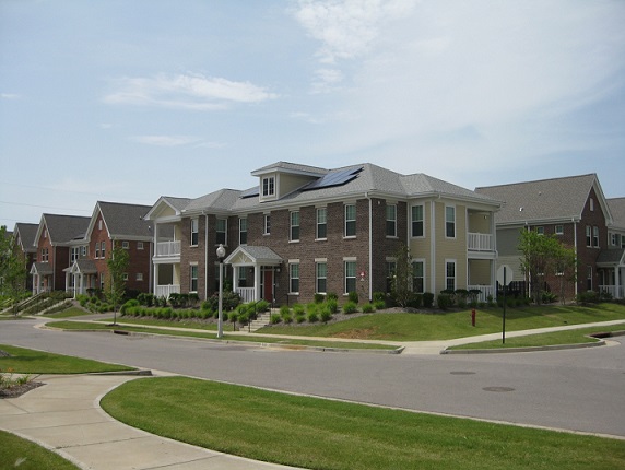 Photograph of a two-story residential building with solar panels on the pitched roof.