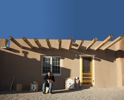 Image of a man sitting in front of a home in Owe’neh Bupingeh, the site of a multiphased project that emphasizes the importance of contemporary life and cultural traditions that comfortably coexist.