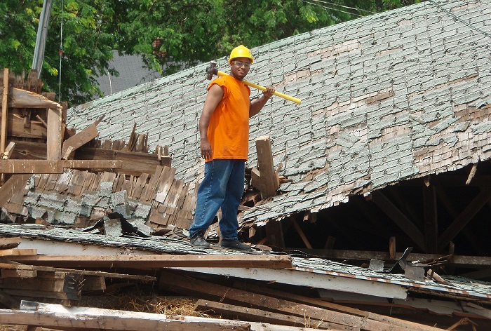 A worker deconstructing a roof.
