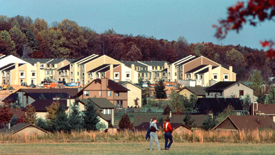 An image of two residents walking in front of a housing development.