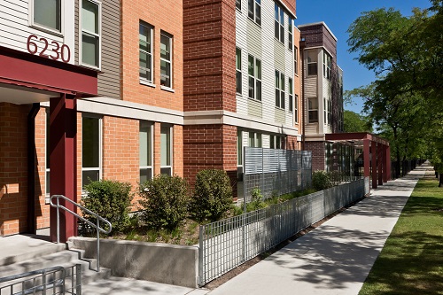 Exterior image of a multistory residential building, with a mixed brick and siding façade. A sidewalk and trees are visible in front of the building. Exterior image of a multistory residential building, with a mixed brick and siding façade. A sidewalk and trees are visible in front of the building.