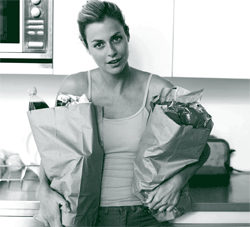 A picture of a woman holding bags of groceries she has bought for her housemate in exchange for reduced rent, per their home sharing contract.