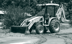 A worker uses a grader to clear a building site.