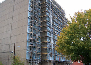Green retrofitting of multifamily housing built prior to 1990 — such as this building that is having insulation added to exterior walls and its windows replaced — can mean substantial savings in energy consumption/costs.