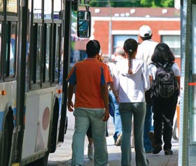 Image of people walking by a bus on a sidewalk.