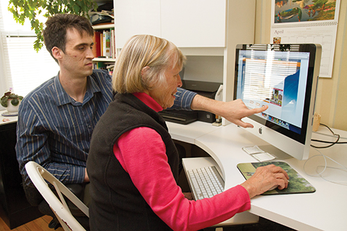 A high school student volunteer tutoring a Newton at Home senior on the use of a computer.