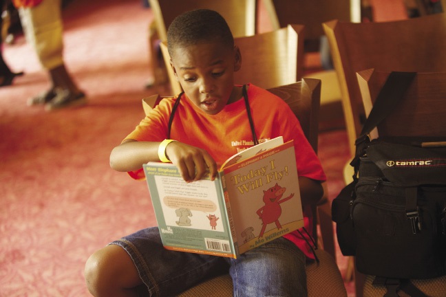 A young boy reading aloud from a book.