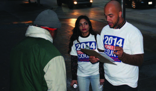 Two homelessness census takers interviewing a homeless man on the street at night.