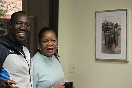 A couple posing in front of a picture of their family.