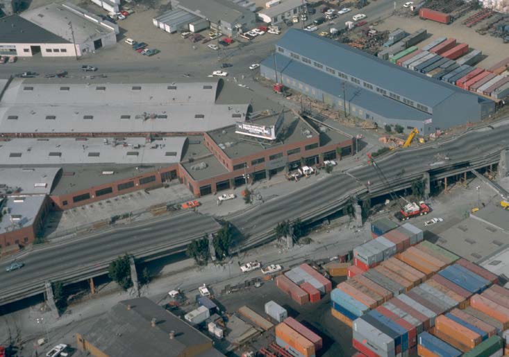 An aerial view of a double-decked freeway viaduct showing the upper deck collapsed onto the deck below. An aerial view of a double-decked freeway viaduct showing the upper deck collapsed onto the deck below.