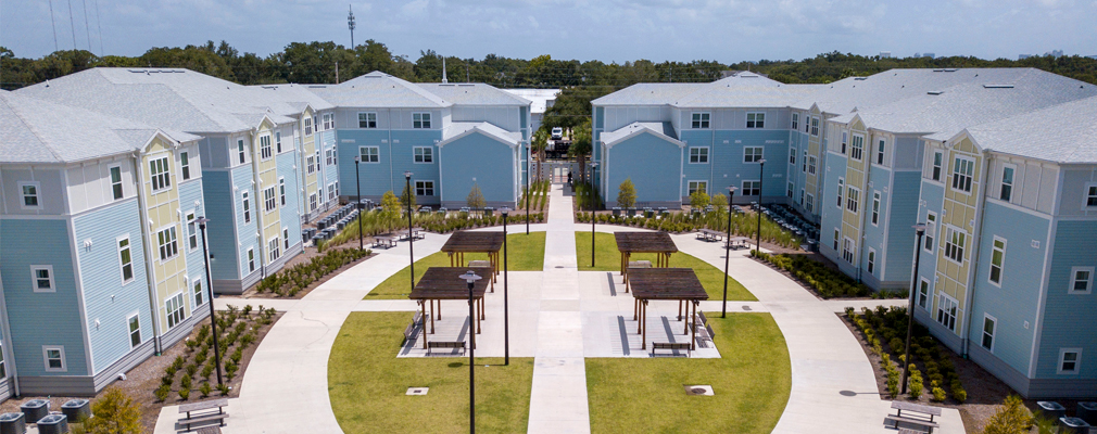 Cluster of three-apartment buildings connected by sidewalks and surrounding a central courtyard.
