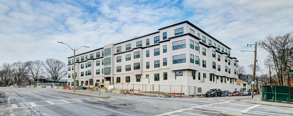 Corner view of white four-story residential building from across the street.