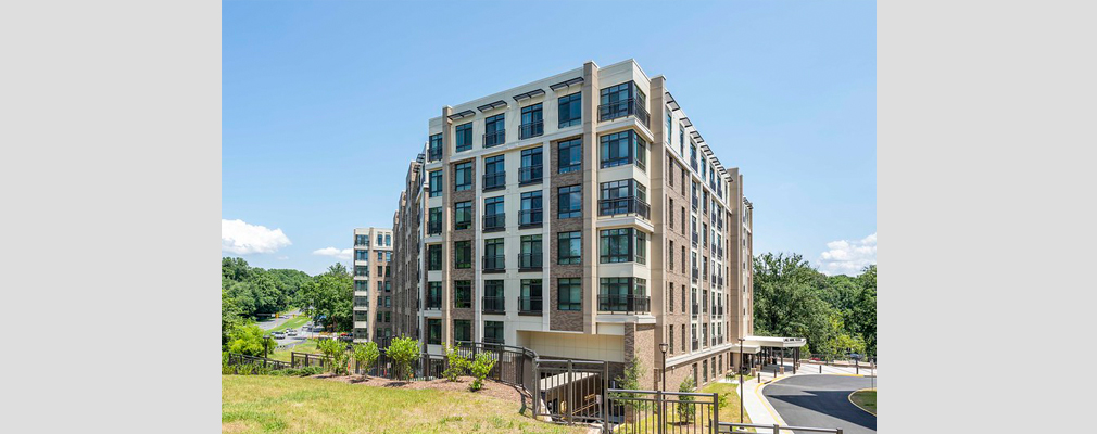 A tall concrete apartment building on a grassy suburban lot.