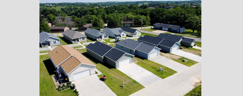 Aerial view of a small suburban community with 10 single-story homes arranged in 2 rows of 5 homes each. Each home has a front yard, narrow side yard, and two-car garage.