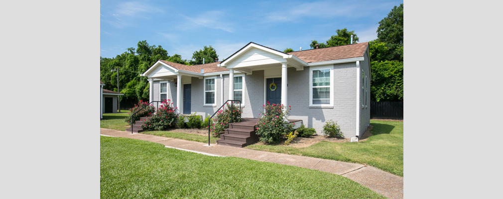 Front view of a single-story Harmony Village duplex with a sidewalk in the foreground.