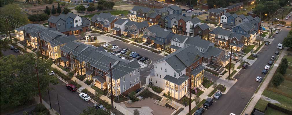 Low-angle aerial photograph taken at dusk of two- and three-story townhouses.