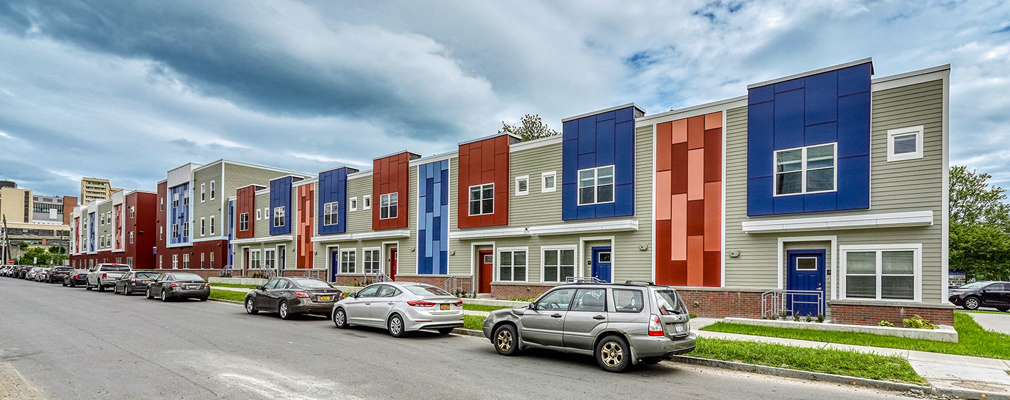 Photograph of the front façade of two-story townhouses and a three-story multifamily building.