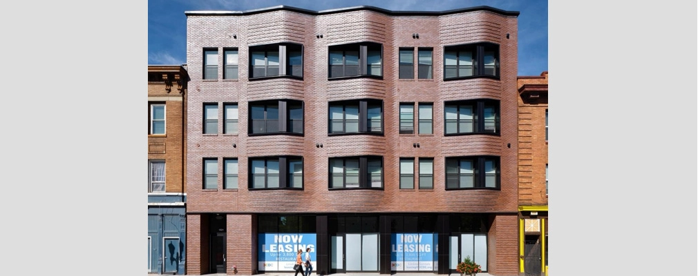  Exterior of four-story apartment building with undulating brick façade.
