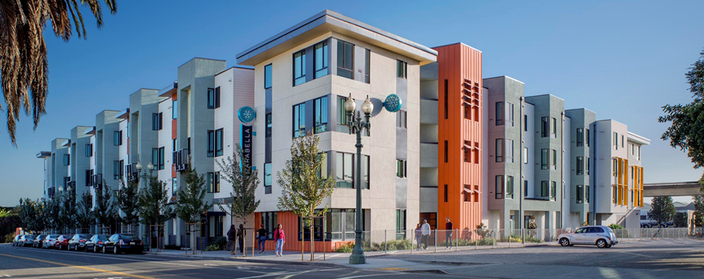 Photograph of two street façades of a four-story multifamily structure.