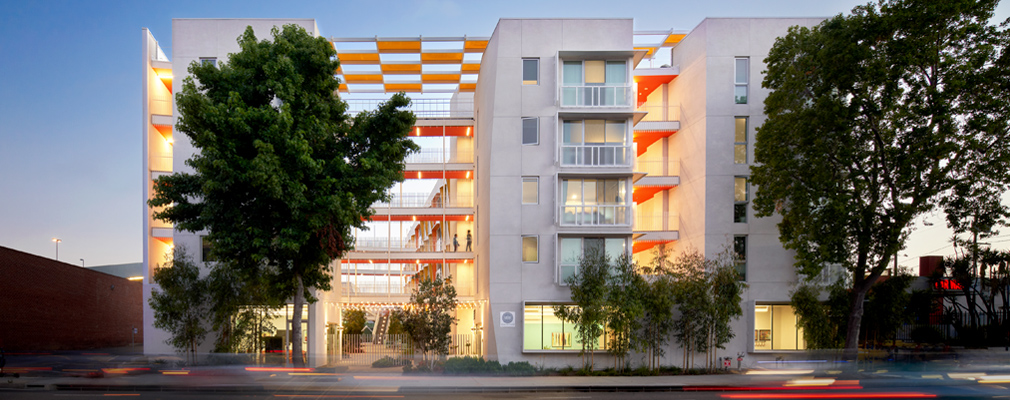 Photograph of the front façade of a multistory residential building in the evening.