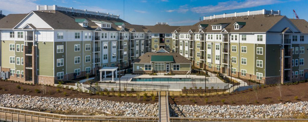 A pool in between two 4-story apartment buildings that face the river and boardwalk.