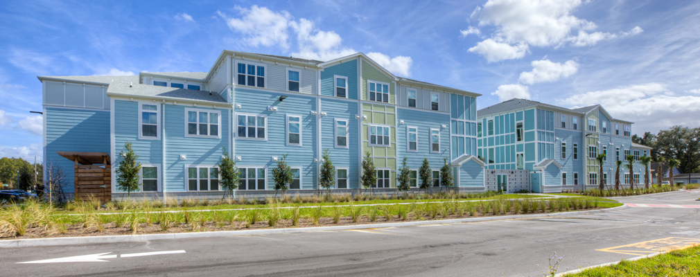 View of a three-story apartment building with a road in the foreground.