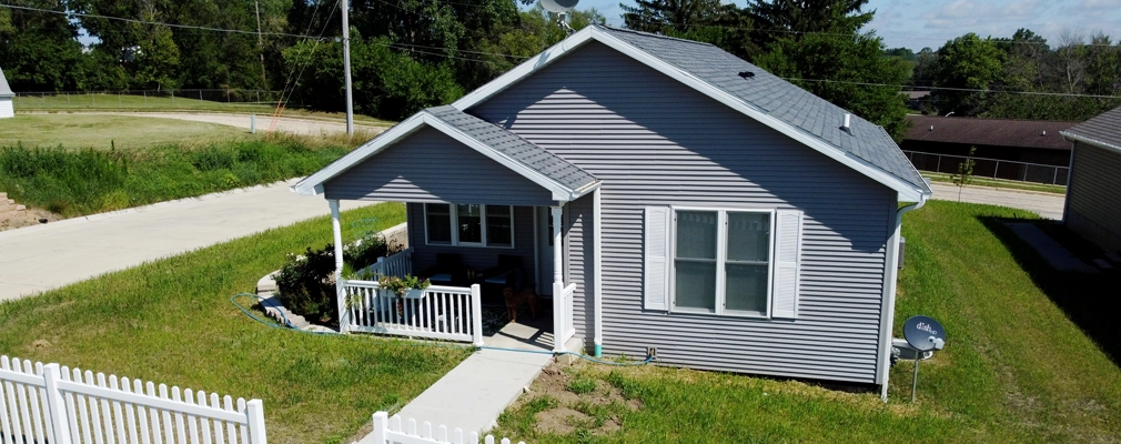 Exterior of a small suburban home with blue siding and a white picket fence
