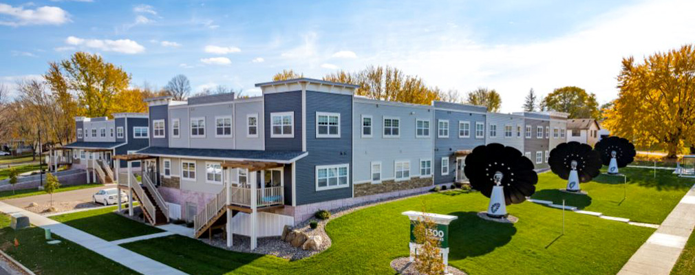 Side view of a two-story multifamily development on a grassy lot.