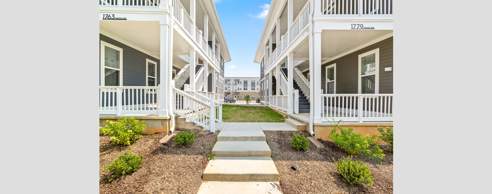 A photograph of 2 two-story quadplex buildings featuring upper and lower porches and exterior staircases.
