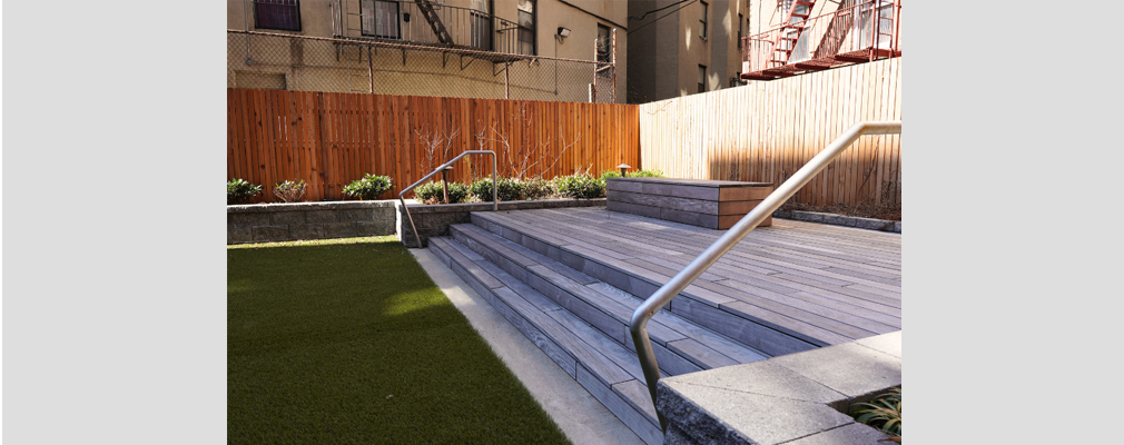 Image of a courtyard with a wooden deck and artificial lawn.