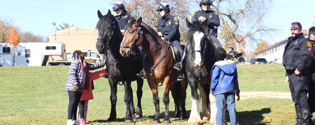 Police officers on horses interact with children.