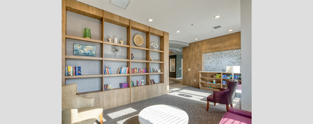 Photograph of large room with upholstered chairs, a coffee table, and bookshelves. 