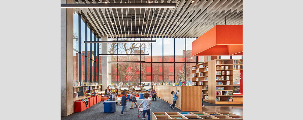 Photograph of several adults and children in the children’s section of a modern library.