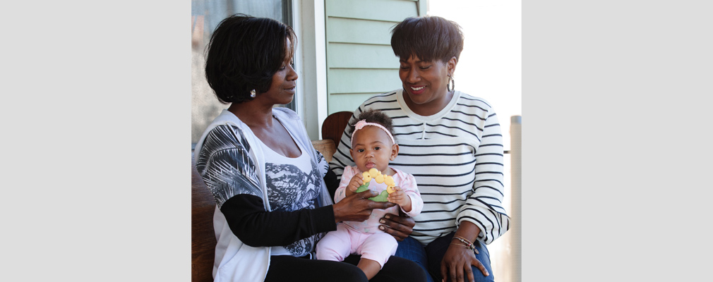 Photograph of two women holding a baby.