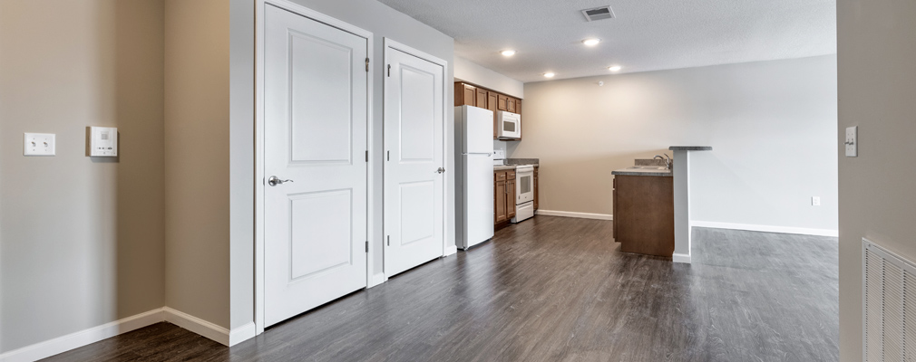 An unfurnished apartment with a kitchen area in the background.