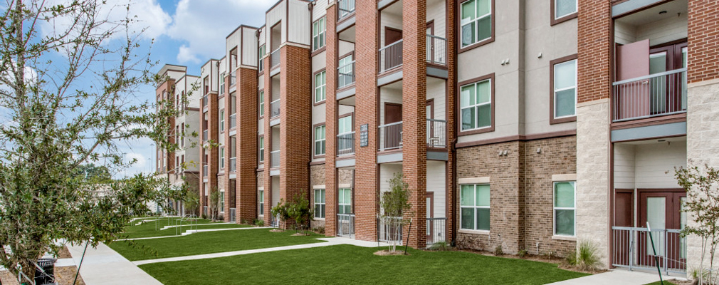 A four-story residential building with walkways connecting to a sidewalk.