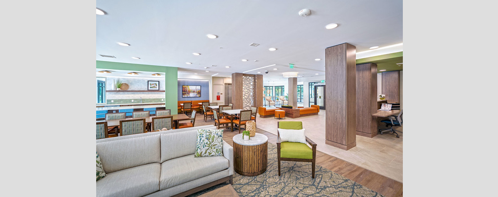 A large, colorful community room with various seating areas and tables with chairs.