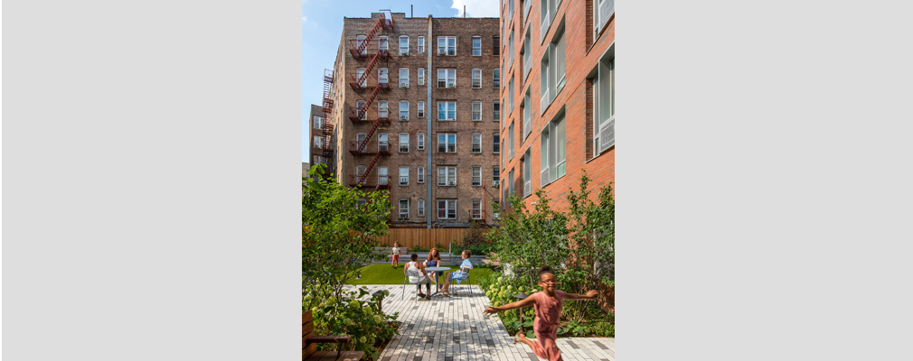 Image of an outdoor courtyard with adults talking around a table and children playing.