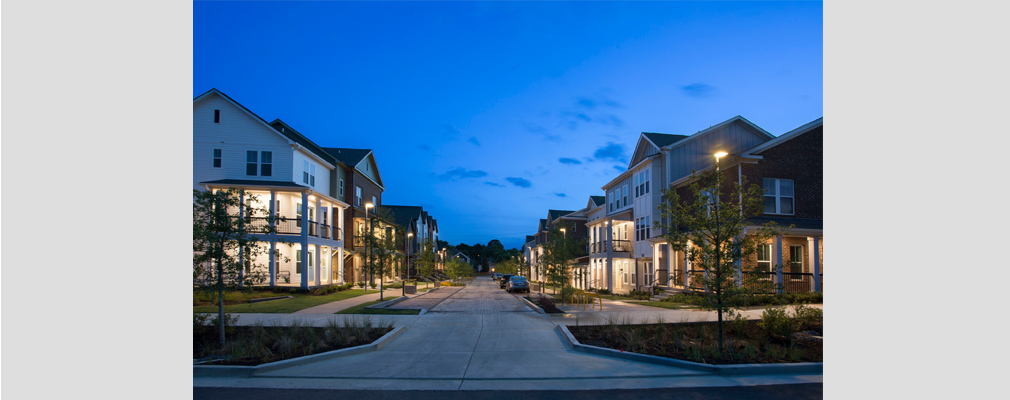 Photograph taken at dusk of a street lined with townhouses. 