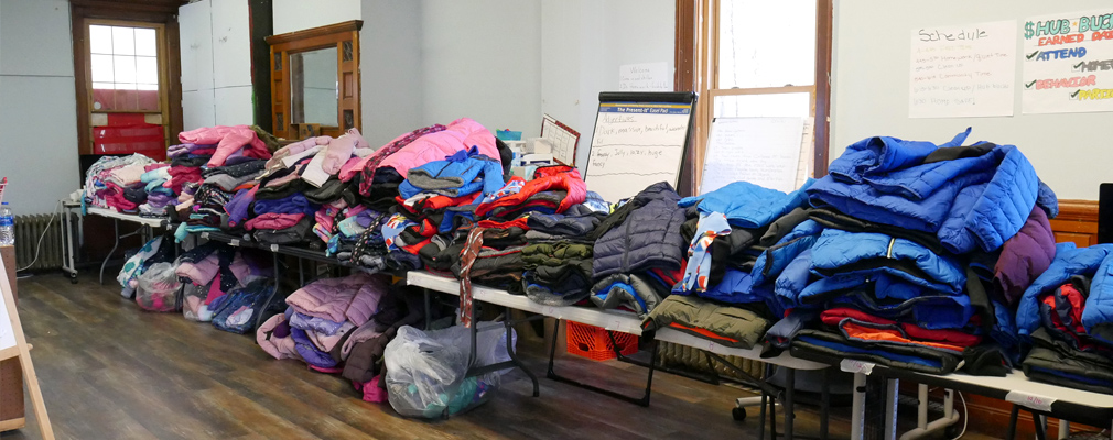 Room full of coats stacked on tables.