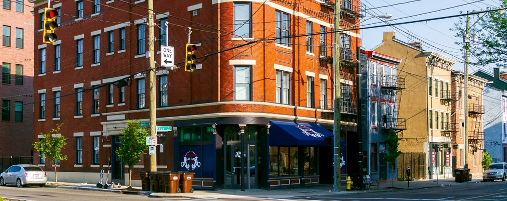 Exterior of historic, four-story, red brick apartment building with ground-level retail on city corner.