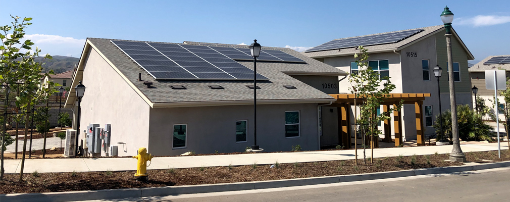 Photograph of one- and two-story residential structures with photovoltaic panels on the roofs.