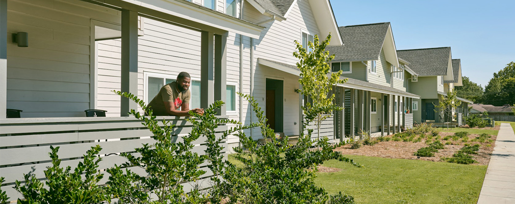 A row of two-story townhomes with one person standing on the front porch of one of the units.